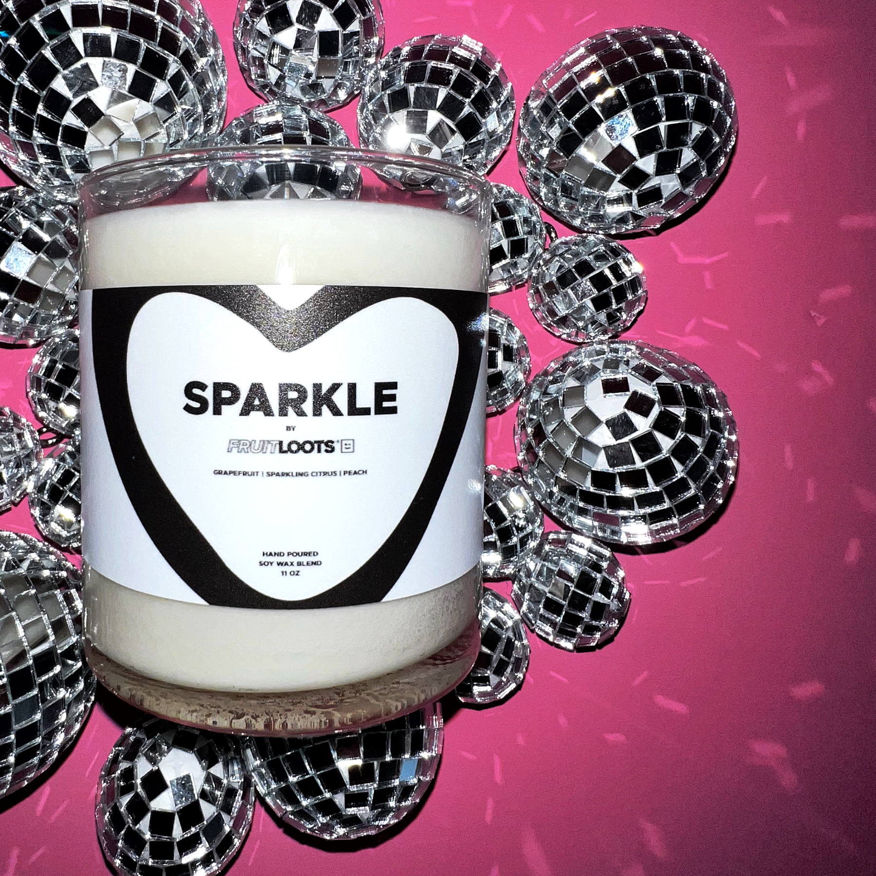 A close up of our candle shows the clear jar, black and white label and tiny disco balls in the backdrop.