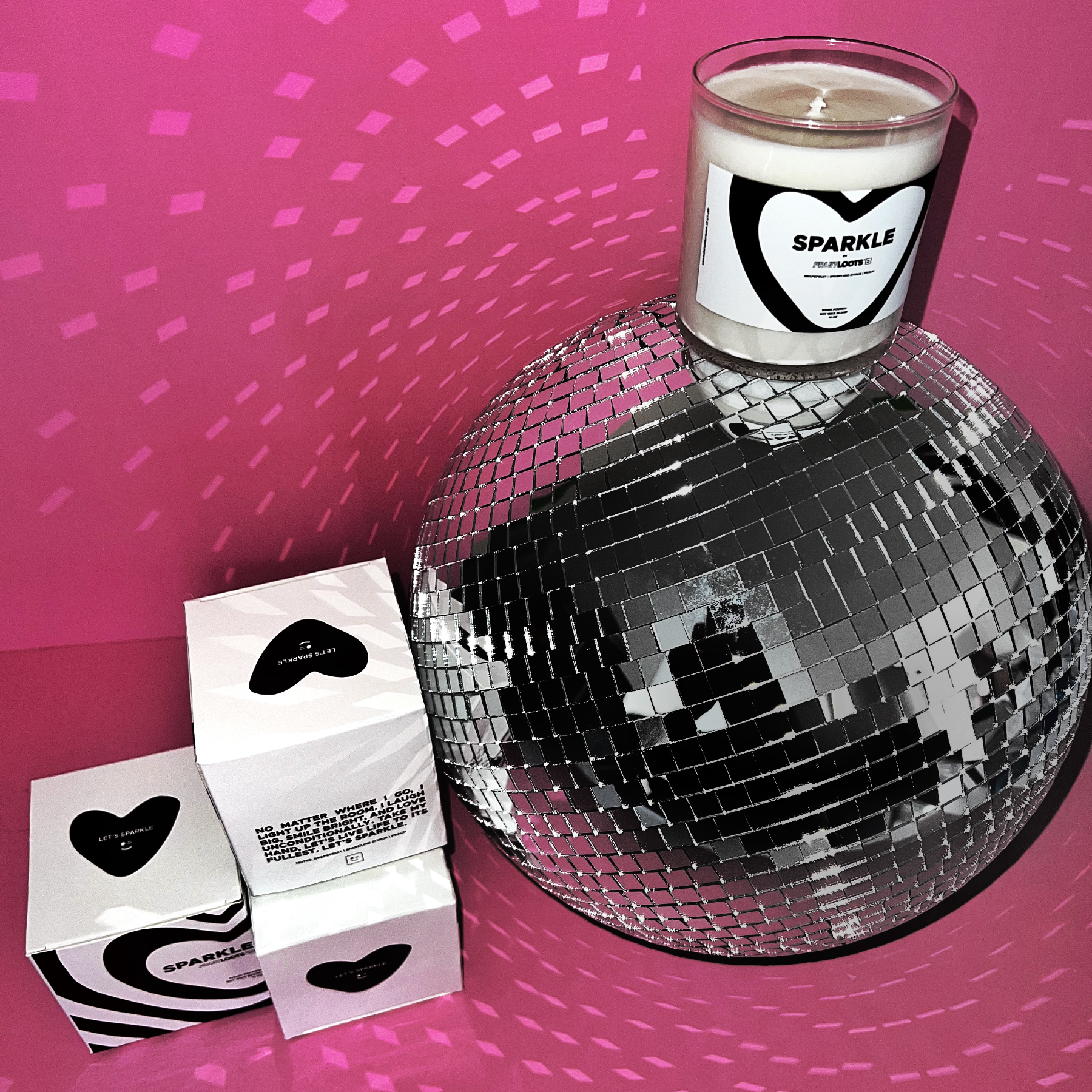 Close up of our packaging sitting on a sparkly disco ball and pink backdrop.