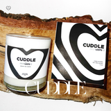 Close up of our Cuddle Candle sitting on a firewood log. 