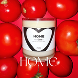 Home candle sitting in a bed of red tomatoes. 